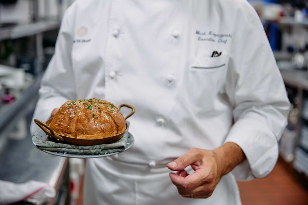 Chef holding artisan bread in a restaurant kitchen.