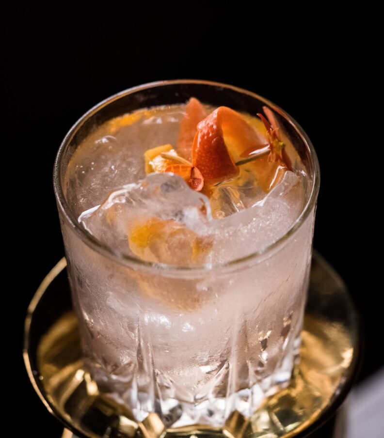 Colorful cocktail displayed on bar counter with ice and garnishes