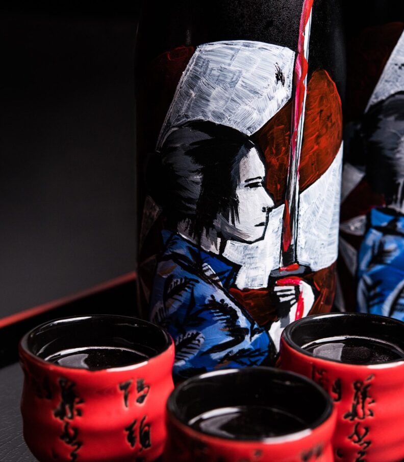 Decorative sake bottles with red ceramic cups on tray