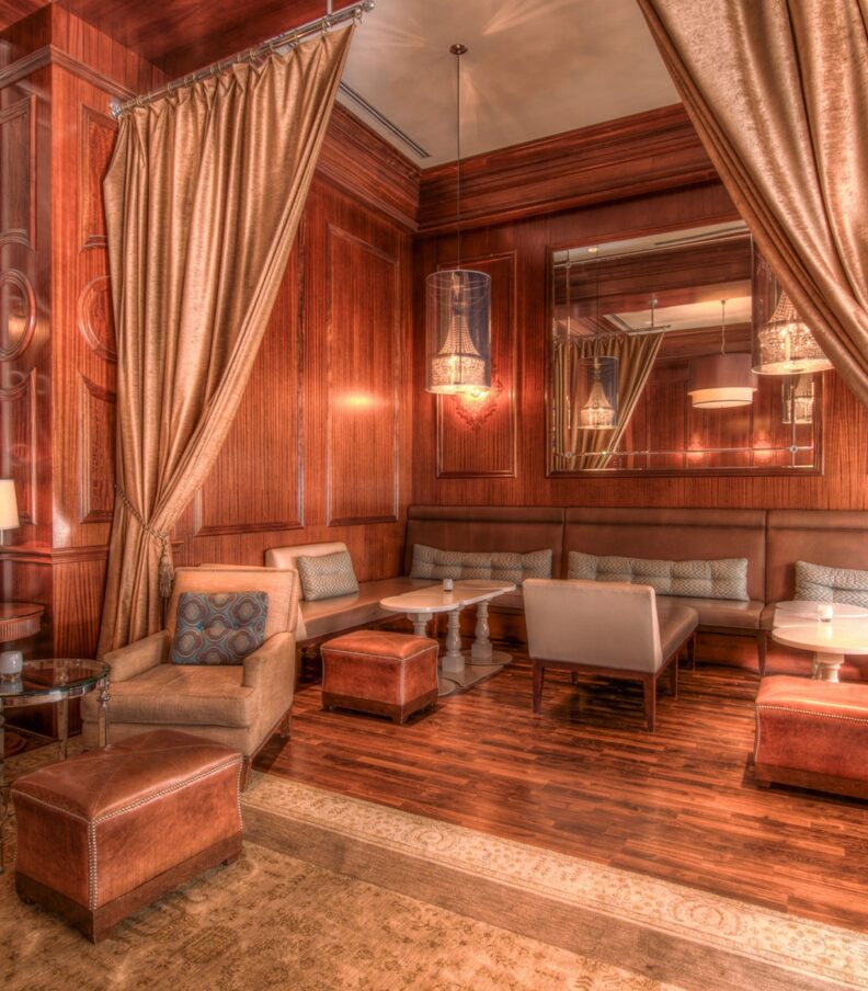 Elegant restaurant lounge with wood paneling, draped curtains, upholstered seating, and soft ambient lighting.
