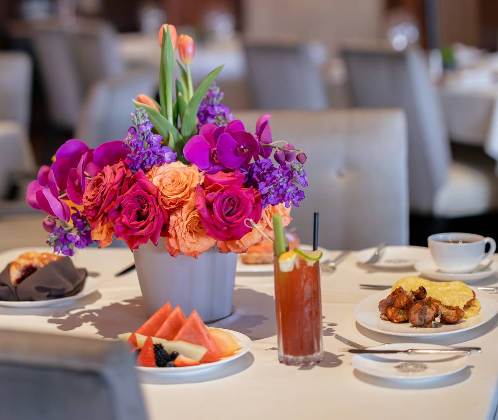 a white table topped with plates of food and a vase filled with flowers